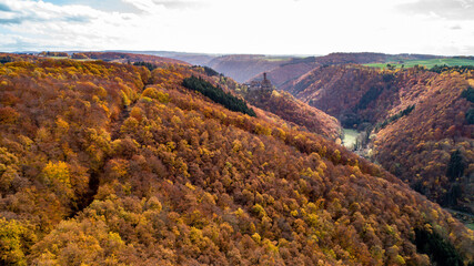 fall autumn aerial view rock with medieval castle Ehrenburg on it near moselle river in Brodenbach with forest hills