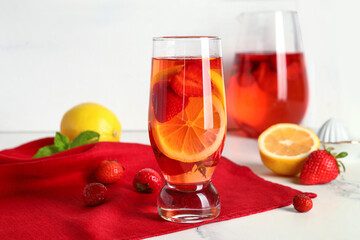 Glass and jug of infused water with strawberry and lemon on white background