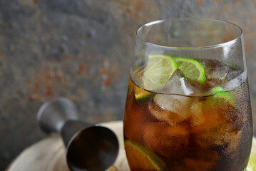 Glass of cold Cuba Libre cocktail on wooden table