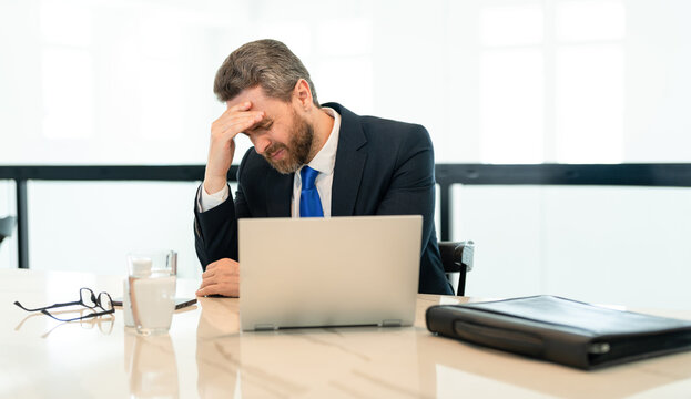 overwhelmed stressed business man has headache. stressed business man has headache in office. stressed business man has headache while working. stressed business man has headache pain.