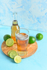 Glass and bottle of cold beer with lime on blue background