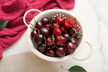 Colander with sweet cherries on white background