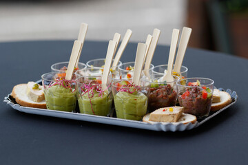 Apéritif verrines dans petits pots en plastique avec une cuillère en bois sur plateau