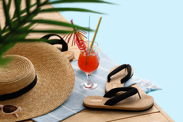 Different beach accessories with plant branches and cocktail on wooden pontoon against blue...