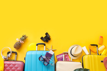 Suitcases with travel set and beach accessories on yellow background. Summer vacation concept