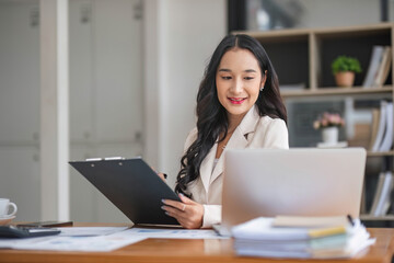 A beautiful and professional Asian businesswoman using her laptop to manage his tasks, working at the office.