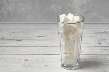 A glass full of white refined sugar on a wooden background. The concept of giving up sugar, as well...