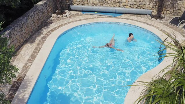 Aerial view of the swimming pool with a young female and female child