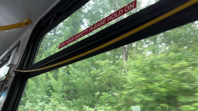 To stop Canadian buses, you need to pull rope, wire will sound stop signal, woman's hand stops bus, press sign, exit, end the journey, green leaves outside bus window, Vancouver Canada, Surrey.
