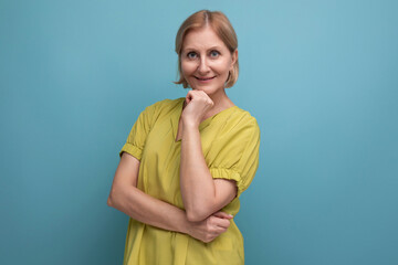 funny blond mature woman in yellow t-shirt having fun on studio background