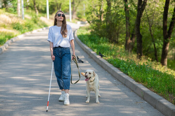 Blind woman walking with guide dog in the park. 