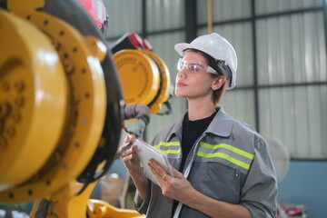 Robotic Arm engineer check on equipment in its with software of an Artificial Intelligence, Programming development technology work. Female industrial engineer working at automated robotic factory..