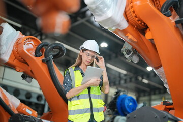 Woman working intently on a complicated industry 4.0 robot plant in technology factory.