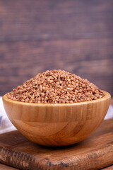 Buckwheat on wood background. Buckwheat grains in wooden bowl