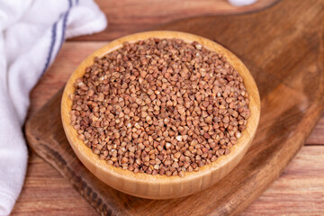 Buckwheat on wood background. Buckwheat grains in wooden bowl