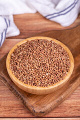 Buckwheat on wood background. Buckwheat grains in wooden bowl