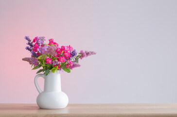 beautiful flowers in white jug on wooden shelf