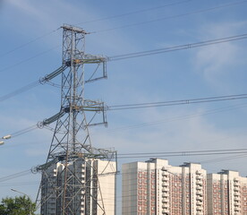 High voltage power lines and pylons in the city. Power lines against the background of residential buildings, ecology.