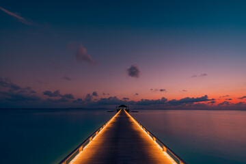 Amazing sunset panoramic beach Maldives. Luxury resort villas long wooden pier seascape with soft...