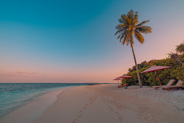 Fototapeta premium Beautiful tropical sunset. Couple sun beds, loungers, umbrella under palm trees. Sand coast sea view with horizon, colorful romantic sky, calm peace love relax. Leisure beach resort amazing landscape