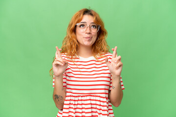 Young caucasian woman isolated on green screen chroma key background with fingers crossing and wishing the best