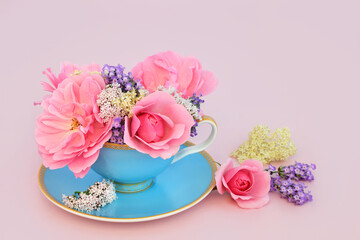 Surreal adaptogen rose, valerian, lavender and elder flower design in tea cup on pink. Fun food herbal medicine composition. Flowers have relaxation health benefits.