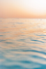 Beautiful closeup sea water surface. Sunset sunrise gold blue colors calm soft waves relaxing horizon. Dream fantasy shallow focus, blur seascape sky. Tranquil peaceful nature pattern, Mediterranean