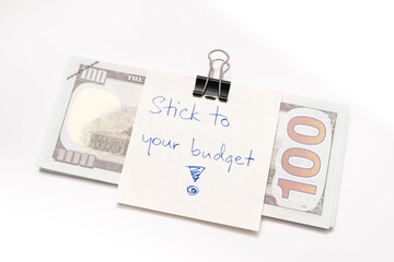 Dollars cash money with text written note STICK TO YOUR BUDGET. concept of financial planning to save money by spending less. Finance and business concept. 