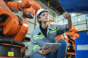 Mechanical engineers with robotic welder., Programming development technology work. Female industrial engineer working at automated AI robotic production factory