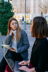 Two business girls having a conversation while working remotely in the city