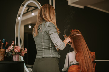 Professional hair stylist combing ginger client hair 