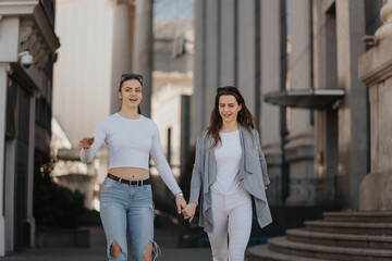 Fototapeta premium Photo of two young women enjoying a sunny day while walking hand in hand through the city