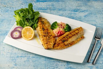 Grilled sea bass fillet served with garnishes in a fine dining restaurant