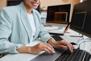 Closeup of smiling young black woman programming code and using computer in office