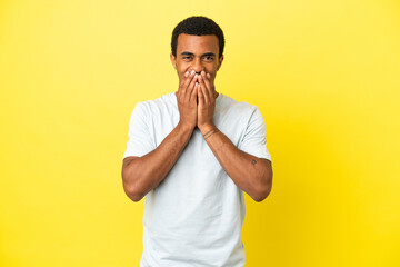 African American handsome man on isolated yellow background happy and smiling covering mouth with hands