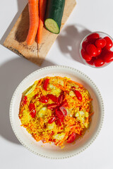 Top vertical view of cous cous with fresh vegetables, cherry tomatoes, cucumber and carrots over a white background