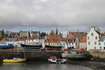 Fototapeta na wymiar A very pretty view of ancient fishermen's cottages crammed together beside the harbour filled with boats in St Monans, Fife, Scotland, UK.