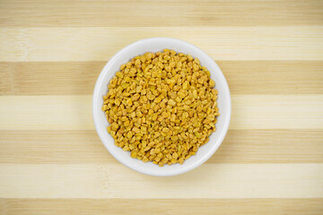 Fenugreek seeds in bowl on wooden background, healthy indian spices