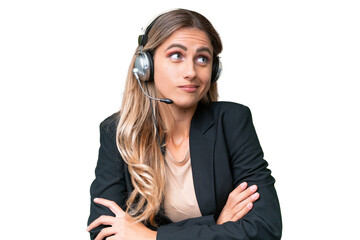 Telemarketer pretty Uruguayan woman working with a headset over isolated background making doubts gesture while lifting the shoulders