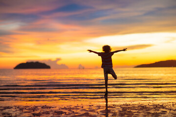 Child playing on ocean beach. Kid at sunset sea.