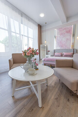 a close view of a tea table with two stylish armchairs in a modern cozy soft interior in warm delicate pastel pink and beige colors