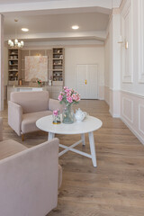 a close view of a tea table with two stylish armchairs in a modern cozy soft interior in warm delicate pastel pink and beige colors