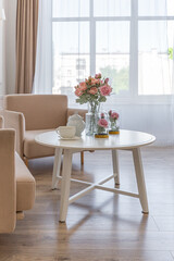 a close view of a tea table with two stylish armchairs in a modern cozy soft interior in warm delicate pastel pink and beige colors