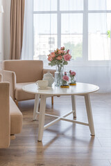 Fototapeta na wymiar a close view of a tea table with two stylish armchairs in a modern cozy soft interior in warm delicate pastel pink and beige colors