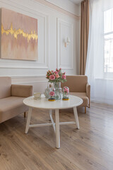 a close view of a tea table with two stylish armchairs in a modern cozy soft interior in warm delicate pastel pink and beige colors