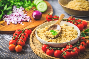 Preparing traditional oriental salad Tabouleh with couscous or bulgur, ingredients on cutting board