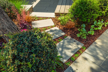 Detail of  garden path with stone slabs with bark mulch and native plants. Landscaping and gardening concept.