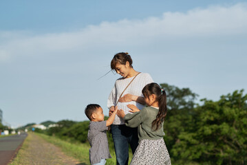 妊娠しているお母さんのお腹に手を当てる子供たち