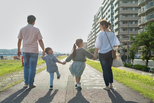 手をつないで歩く家族の後ろ姿