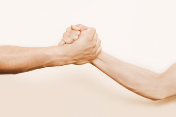 The strong hand of a man holds the hand of a weaker man and pulls him up, as if saving him from a...